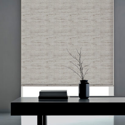 Minimalist interior design with white roller blind, black vase with branches, and stack of books on a black table.